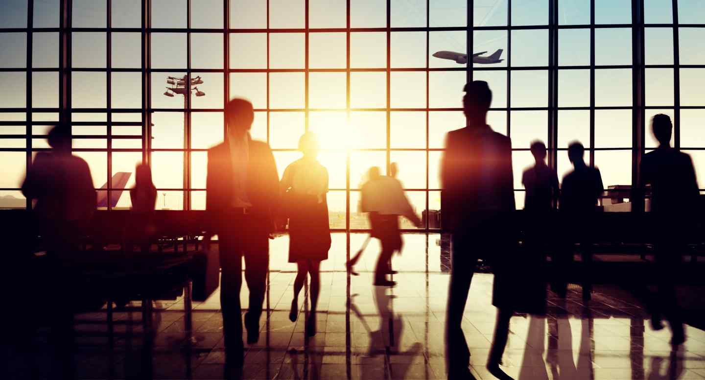 silhouettes watching planes take off from inside an airport terminal